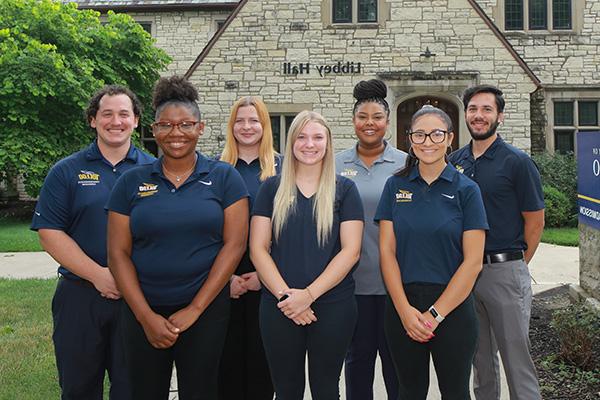 A diverse group of admission counselors standing together on UToledo's campus, smiling at the camera