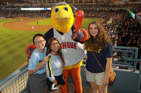 Students standing with Mud Hens mascot Muddy at a Mud Hens game